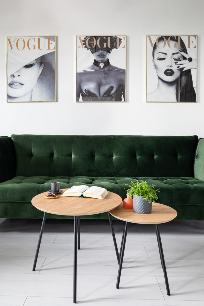 Apartament na wynajem. Zielona sofa, obrazy i przedmioty do aranżacji na stolikach.